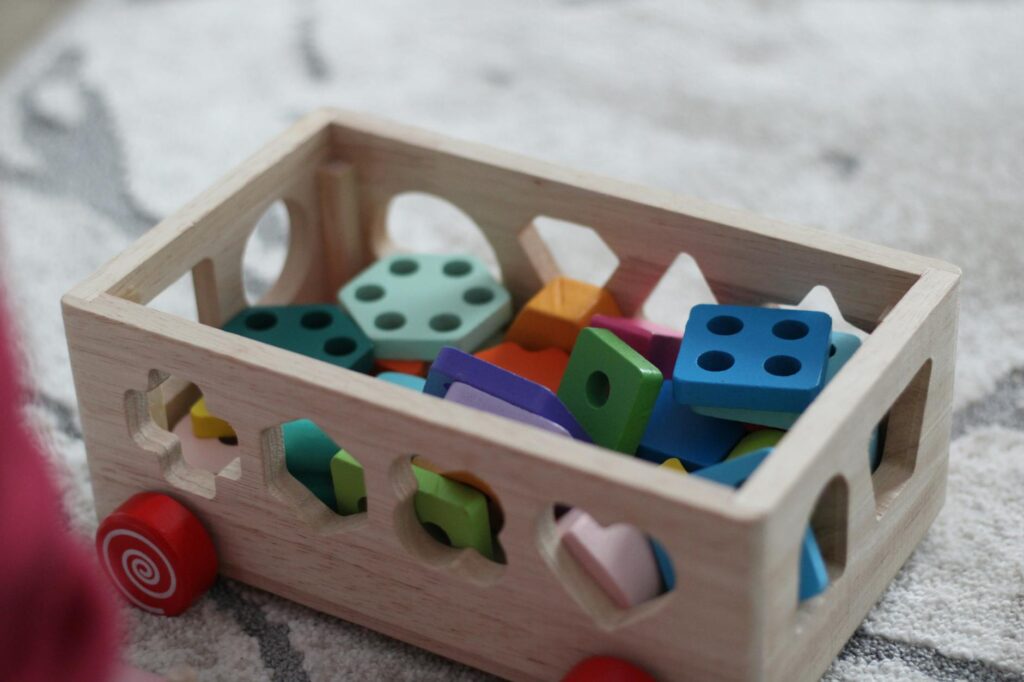 Enfant de deux ans manipulant des blocs colorés en bois sur un tapis d'éveil