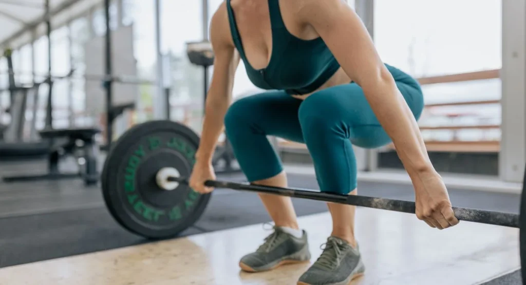 Femme concentrée en tenue de sport contracte ses muscles en salle sombre