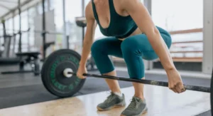 Femme concentrée en tenue de sport contracte ses muscles en salle sombre