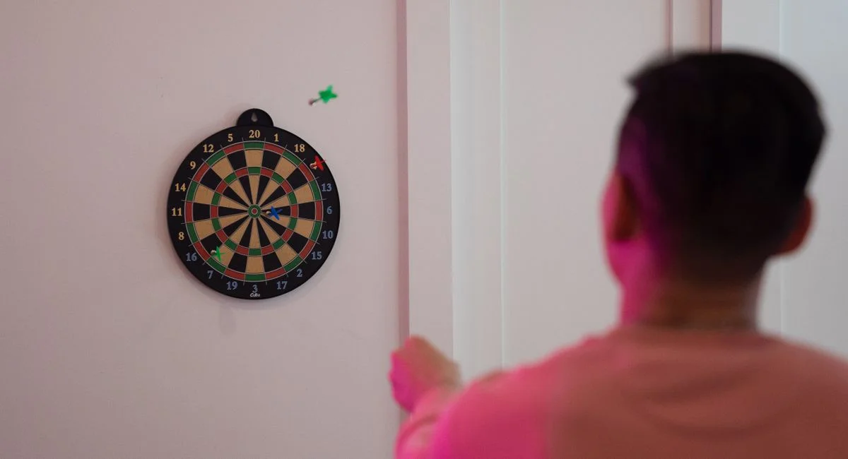 A person aims at a dartboard on a wall, showcasing precision and focus.